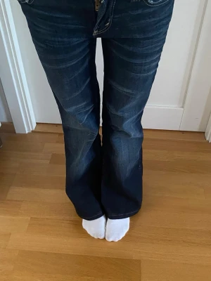 Mörkblå bootcut jeans - Säljer ett par mörkblå bootcut jeans med snygga slitningar Innerbenslängd 66 cm och midja 32cm. Passar mig som är 155. Använda 2ggr skriv för fler frågor!🥰🍒