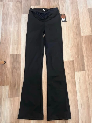 Utsvängda träningsbyxor - Säljer ett par svarta leggings från gekås med bootcut-modell. Stretchigt material som sitter skönt och följer kroppen. Perfekta för dig som gillar en stilren look med lite vidare ben. Lappen sitter kvar.