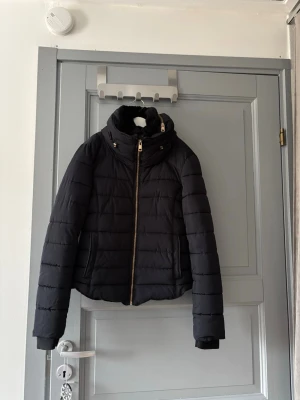 Vinterjacka  - Säljer en stilren vinterjacka i kortare modell. Varm och skön, perfekt för kalla dagar – både till vardags och mer uppklädda outfits. Extra dragkedjor baktill i sidorna för justerbar passform. Jackan är i fint skick och sparsamt använd.