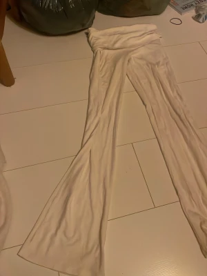 Vita utsvängda yoga pants - Säljer ett par vita leggings med utsvängda ben och hög midja. De är mjuka och stretchiga, perfekta för en trendig och bekväm look. Passar dig som gillar en avslappnad men ändå snygg stil.