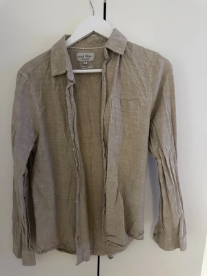 Beige linneskjorta från Cool Blue - Snygg beige skjorta från Cool Blue i linne med klassisk krage och bröstficka. Skjortan har långa ärmar med manschett och knappar framtill. Perfekt för en avslappnad men stilren look.