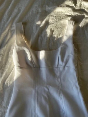 Vit klänning från H&M Divided - Säljer en stilren vit topp från H&M Divided i storlek XS. Toppen har breda axelband, fyrkantig urringning och är figurnära i modellen. Perfekt för sommarens alla tillfällen. Aldrig använd 💓