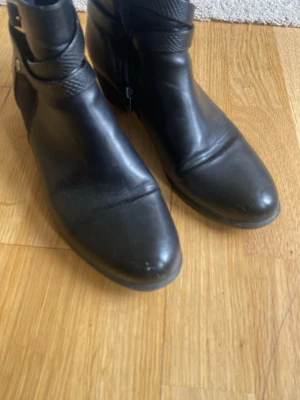 Svarta boots  - Snygga svarta boots tå och dekorativt spänne runt ankeln. Dragkedja på sidan för enkel på- och avtagning, en dragkedja har lite svårt att dras upp Perfekta till jeans eller kjol för en cool look.