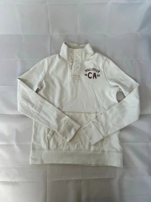 Vit Hollister hoodie vintage - En riktigt fet hollister tröja! Sitter som M och mycket bra på och har fint skick. | Skick:9/10 | modellen är 185cm lång‼️ Mått armhåla-armhåla 52cm och armhåla-slut 45cm. Pris 599 men kan diskuteras😁☺️🤩