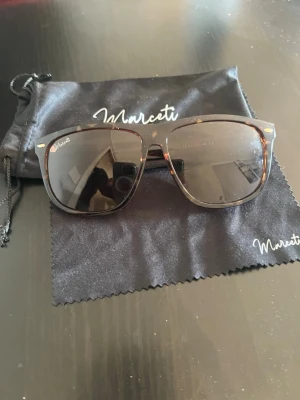 Bruna solglasögon - Snygga solglasögon från Marceti med brunmelerat sköldpaddsmönster och bruna glas. Klassisk fyrkantig form som ger en cool vibe. Perfekta för soliga dagar när du vill sticka ut lite extra. Perfekt för den som vill klä sig i grisch stilen