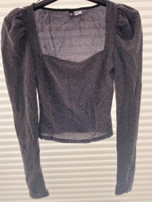 Glittrig långärmad topp H&M - Snygg glittrig topp från H&M med fyrkantig urringning och puffiga axlar. Toppen är långärmad och har en croppad passform. En mycket bra skick. Storlek: S