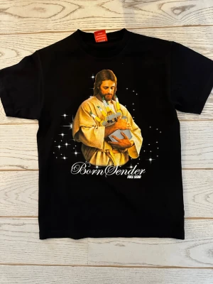 Svart Full Send t-shirt - Cool svart t-shirt från Full Send med ett stort tryck framtill av en person i guldfärgad dräkt och texten 'Born Sender. T-shirten har korta ärmar och klassisk passform. Perfekt för dig som gillar statement-plagg.