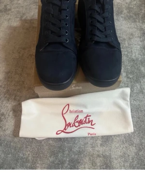 Mörkblå sneakers från Christian Louboutin - Snygga mörkblå sneakers från Christian Louboutin i mocka med matchande mörkblå skosnören och diskret design. Klassisk låg modell med rund tå och svart sula. Perfekta för dig som vill ha en stilren och exklusiv look.