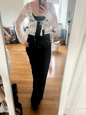 Vit spetskofta med knytband - Säljer en superfin, somrig vit spetskofta med långa ärmar och  blommönster. Koftan är kort, har knytband framtill och är genomskinlig med fina detaljer längs kanterna.  Passar perfekt över linne eller annan topp. Säljer pga att den är lite för liten för mig. 