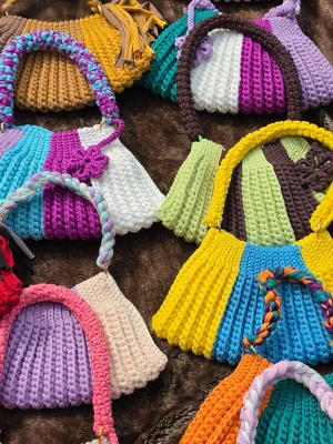 Flerfärgad virkad handväska - Unik handväska i virkad design handtaget och axelband. Dekorerad med en liten virkad blomma. Perfekt för dig som gillar färg och unika accessoarer.