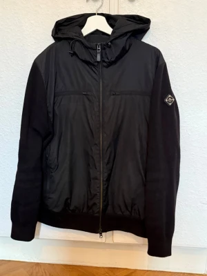 Svart j Lindeberg cardigan/jacka - Snygg svart cardigan från J Lindeberg! Säljer då jag inte använder den längre. I mycket fint skick, men ett superlitet hål/söm som gått upp på armen, syns knappt men kan skicka bild vid intresse! 