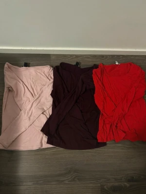 3 långärmade toppar från Newyorker - Säljer tre långärmade toppar från Newyorker i olika färger: ljusrosa, mörklila och röd. Alla har rund halsringning och är tillverkade i mjuk bomullsmix. 