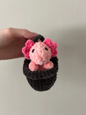 Virkad axolotl - Virkad axolotl med en liten hink i mjukt garn, axolotln är cirka 10cm hög utan hinken☺️