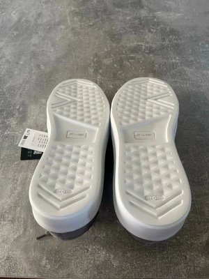 Gråa sneakers i mocka från Jack & Jones - Snygga grå sneakers från Jack & Jones med ovandel i mjuk mocka och vita, rejäla gummisulor. Klassisk låg modell med matchande grå skosnören och diskret design som passar till det mesta. Perfekta för dig som gillar stilrena och bekväma skor.