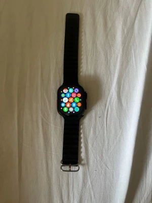 Svart smartklocka med silikonarmband - Snygg svart smartklocka med fyrkantig pekskärm och svart silikonarmband. Klockan har en modern design med många appar och funktioner på displayen. Perfekt för dig som vill ha koll på notiser, hälsa och träning direkt på handleden. Helt NY!