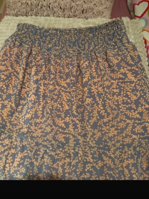 Blommig kortkjol i blått och beige - Supersöt kortkjol med blommigt mönster i beige på blå botten. Kjolen har bred resår i midjan för skön passform och är gjord i ett lätt och luftigt material, perfekt för varmare dagar. Passar perfekt till en enkel topp eller stickad tröja.