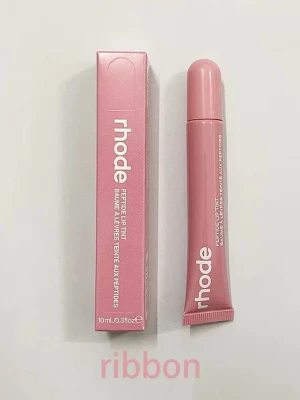 rhode Peptide Lip Tint Ribbon - Säljer ett rhode Peptide Lip Tint i färgen Ribbon, en mjukt rosa nyans. Läppglanset kommer i en smidig tub med vit text och matchande rosa förpackning. Innehåller 10 ml och ger en glossig finish med lätt tint.