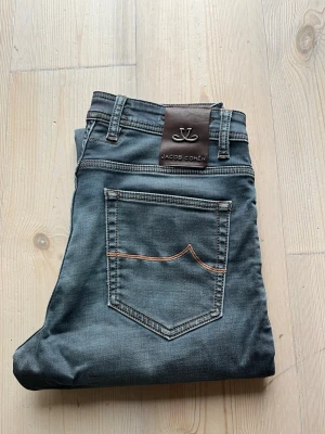 Jacob Cohën Jeans - Säljer nu dessa snygga Limited Edition Jacob Cohën jeans!  Den har färgen grå/blå, och har en snygg wash.   Storleken är 31, och jag skulle säga att den sitter som det också, alltså är den true-to-size. Passformen är 688, alltså sitter den som slim.  Skicket är 9/10, använda några gånger, men fortfarande otroligt fint skick och utan fläckar.  Nypriset är 4999 kr❌ Mitt pris är 1299 kr✅  Om du har några frågor eller funderingar är det bara att fråga, och priset är inte hugget i sten!🤝🤗