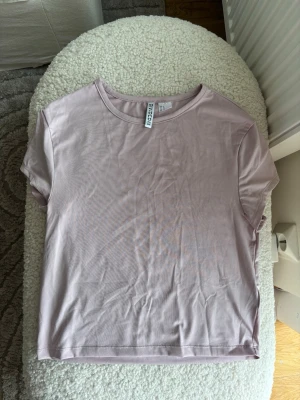 Ljusrosa basic t-shirt från H&M Divided - En enkel och stilren ljusrosa t-shirt från Divided H&M. T-shirten har rund halsringning och korta ärmar. Tillverkad i mjuk bomull som känns skön mot huden. Perfekt att matcha med jeans eller kjol för en clean look.
