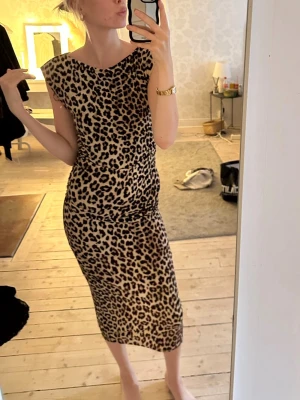 Leopardmönstrad långklänning - Säljer en snygg långklänning med leopardmönster. Klänningen har en figurnära passform, rund halsringning och är ärmlös. Perfekt för dig som vill sticka ut med ett djurmönster och gillar trendiga detaljer.