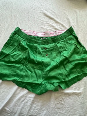 Gröna boxershorts från Pink - Snygga gröna boxershorts från Pink med vit resår och rosa text. Tillverkade i mjukt och lätt material som känns skönt mot huden. Klassisk passform med knappgylf och elastisk midja för extra komfort.