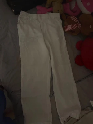 Vita raka linnebyxor - Säljer ett par vita linnebyxor med rak passform och resår i midjan. Byxorna har en enkel och clean look, perfekta för en avslappnad och stilren outfit. Materialet är luftigt linne som passar bra till varmare dagar.