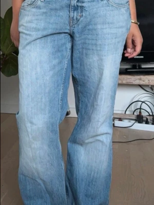 Ljusblåa raka jeans y2k - Säljer ett par ljusblå jeans med rak passform och klassisk femficksdesign. Jeansen har en avslappnad siluett, snygga slitningar och tvättade detaljer. Tillverkade i denim för en tidlös look.