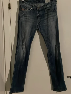 Blå raka jeans med slitningar - Ett par skit snygga Diesel jeans med ett par år på ryggen därav så har den en ganska sliten och unik design. Storlek 31/32 i en slim fit passform men dem är mer straight legged skulle ja säga. tveka ej av att hlra av er 🥂👍🫡