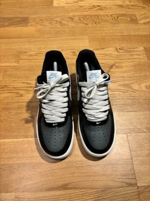 Nike Air Force 1 – Stilren Svart/Grå Modell - Säljer ett par fräscha Nike Air Force 1 i en snygg färgkombination med svarta och grå detaljer. En av de mest ikoniska sneakersen som kombinerar komfort med en tidlös streetwear-look. Skorna är i mycket fint skick och redo för nästa ägare. 