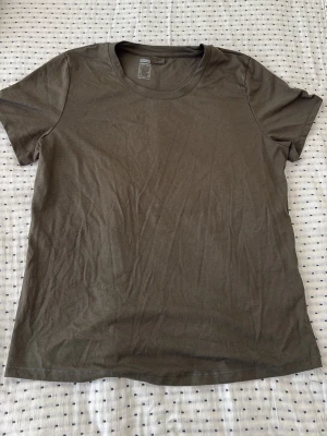 Olivgrön basic t-shirt - En enkel olivgrön t-shirt med rund hals och korta ärmar. Tillverkad i mjuk bomull, perfekt för en avslappnad stil. Passformen är normal och modellen är klassisk utan tryck eller mönster.