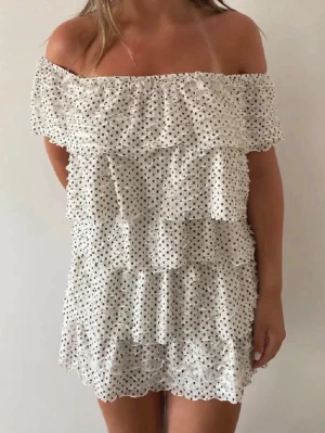 Vit offshoulder prickig volangklänning Zara viral eftertraktad  - Supersöt kort offshoulder klänning i vitt med svarta prickar och volanger från Zara! Inga hål eller lösa trådar, det svarta bandet tillkommer! Passar mig som bär S