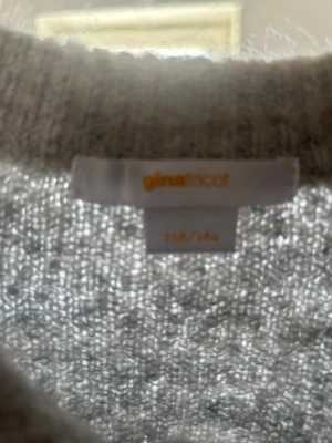 Grå kofta från Gina Tricot - Mysig grå kofta från Gina Tricot med rund halsringning och knappar framtill. Koftan är stickad i ett mjukt material och har halvlånga ärmar. Perfekt att slänga över en topp för en avslappnad look.