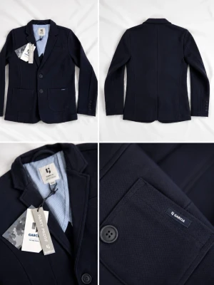 Mörkblå kavaj från Garcia - Stilren mörkblå kavaj från Garcia med tvåknappsdesign, klassisk krage och två framfickor. Innerfodret är ljusblått med ränder. Perfekt för en dressad look och passar till skjorta eller t-shirt. Materialet känns mjukt och följsamt.