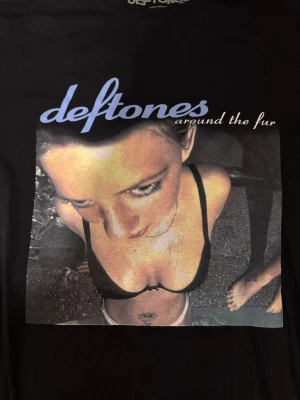 Deftones Around the Fur t-shirt - Säljer en svart t-shirt med stort tryck av Deftones album 'Around the Fur' på framsidan. T-shirten har klassisk passform och korta ärmar. Perfekt för dig som gillar bandmerch och vill ha en ikonisk look. Passar mer storlek S
