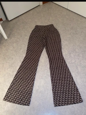 Bruna mönstrade bootcut leggings - Jättesnygga mönstrade flare-byxor från NA-KD i bruna, beige och vita toner. Byxorna har en hög midja, dold dragkedja i sidan och ett superfint fall med ordentligt utsvängda ben. Passar perfekt både till vardags och fest! Sitter väldigt smickrande på.