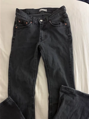Svarta skinny jeans med fem fickor - Snygga svarta flare/bookcut jeans med klassisk femficksdesign och knappgylf. Jeansen har en något tvättad look och smal passform och som sitter löst längs benen. Perfekta att matcha med sneakers eller boots för en cool stil.