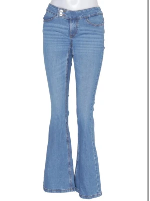 Blå bootcut jeans med dubbla knappar - Snygga ljusblå bootcut jeans med dubbla knappar i midjan och klassiska fickor fram och bak. Storlek M men mer som en S