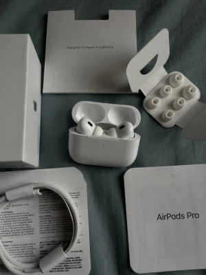 Apple AirPods Pro  - Säljer ett par vita Apple AirPods Pro med trådlöst laddningsetui. Hörlurarna har silikonproppar i flera storlekar och levereras med originalförpackning och tillbehör som laddningskabel och extra öronproppar. Snygg och stilren design i matt plast.