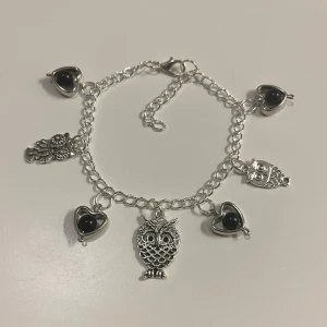 Silverfärgat armband med ugglor och hjärtan - HANDGJORT Snyggt silverfärgat armband med flera berlocker i form av ugglor och hjärtan. Armbandet har en förlängnings kedja.