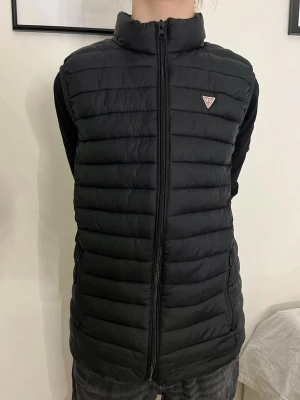 Svart dunväst från Guess - Snygg svart dunväst från Guess Jeans, orginalpris när ja köpte var 1200kr å den är aldrig använd. Priset går att diskuteras 