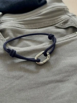 Navy armband  - Stilrent armband med mörkblått snöre och ett silverfärgat metallspänne i form av en liten karbinhake. Justerbar storlek tack vare knutarna. Perfekt accessoar för en enkel men cool look.