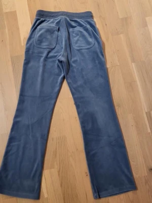 Blå velour mjukisbyxor med fickor från Lindex  - Mysiga blå mjukisbyxor i velour med raka ben och resår i midjan. Byxorna har snörning framtill och praktiska fickor både fram och bak. Perfekta för chill dagar eller när du vill vara extra bekväm. ⚠️en bakficka är lite sönder⚠️