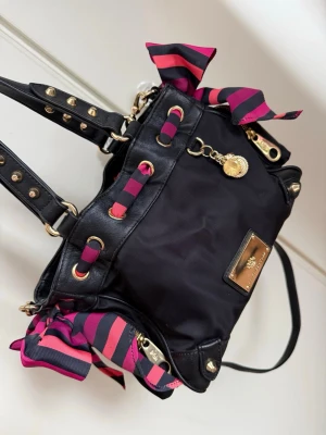 Juicy Couture väska - Väldigt gammal juicy couture väska som legat i en byrå utan användning, köptes begagnad för flera år sedan. Väskan har små skavanker, men fortfarande fin. Den har rosetter på sidorna som man kan knyta hur man vill, fickor både inne och utanpå väskan.