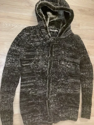 Fodrad stickad cardigan - Otroligt snygg, varm och skön svart grå fodrad stickad cardigan med fint mönster. Passar perfekt till kallare väder. Priset kan såklart diskuteras!