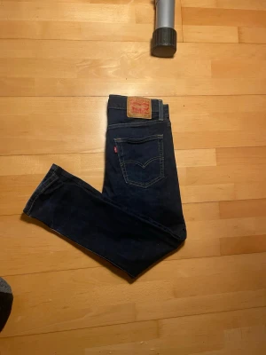 Mörkblå Levi's jeans herr - Säljer ett par mörkblå jeans från Levi's med klassisk femficksdesign och raka ben. Jeansen har Levi's ikoniska läderpatch bak i midjan och röda logotag på bakfickan. Tillverkade i slitstark denim, perfekta för en avslappnad och stilren look. Skriv vid minsta fundering🤩