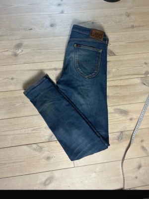 Blå jeans från Lee Malone W31 L34 - Säljer ett par klassiska blå jeans från Lee, modell Malone. Jeansen har en snygg tvätt, raka ben och fem fickor. Tillverkade i bomull med Lee-lapp bak i midjan. Perfekta för en avslappnad och trendig stil. Ta antigen båda eller köp ena om det är av större intresse! Priset går att diskutera!!