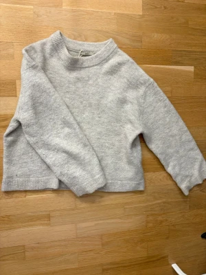 Ljusbeige stickad tröja - Mysig ljusbeige stickad tröja med rund halsringning och ribbade muddar vid ärmslut och nederkant. Tröjan har en avslappnad passform och är perfekt för lager på lager. Passar till både jeans och kjol.