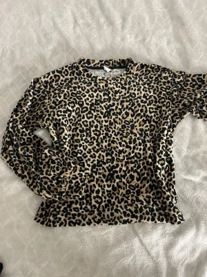 Leopardmönstrad tröja från Lindex - Säljer en långärmad tröja från Lindex med leopardmönster i beige, svart och brunt. Tröjan har rund halsringning och är tillverkad i mjukt material som känns skönt mot huden. 