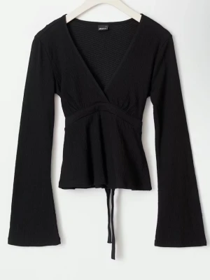 Svart omlottopp med knyt från Gina tricot  - Stilren svart omlottopp från Gina tricot med långa ärmar och v-ringad hals. Nyskick. 