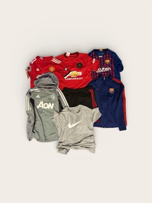 Klädpaket Fotboll (147-158) – Man Utd, Barça & Nike - Säljer ett stort paket med fotbollskläder för junioren. Blandning av matchtröjor med spelarnamn och funktionella träningsplagg.  Perfekt garderobsuppdatering för den fotbollstokiga.  Skick: Överlag fint begagnat skick på samtliga plagg. Hela och rena.  Storlek: Varierande mellan 147–158 (passar ca 10–13 år).  Pris:  Styckpris: 249 kr/st (Säljer helst hela paketet).  Paketpris (Allt på bilden): 1 250 kr 